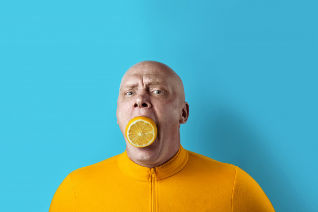 bald brutal man with lemon in his mouth and yellow jacket on blue background 105538 197
